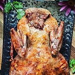whole roasted duck on a platter on the counter.
