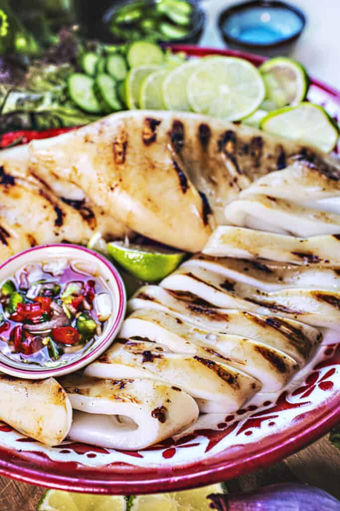 Thai Grilled squid with dipping sauce on a tray.