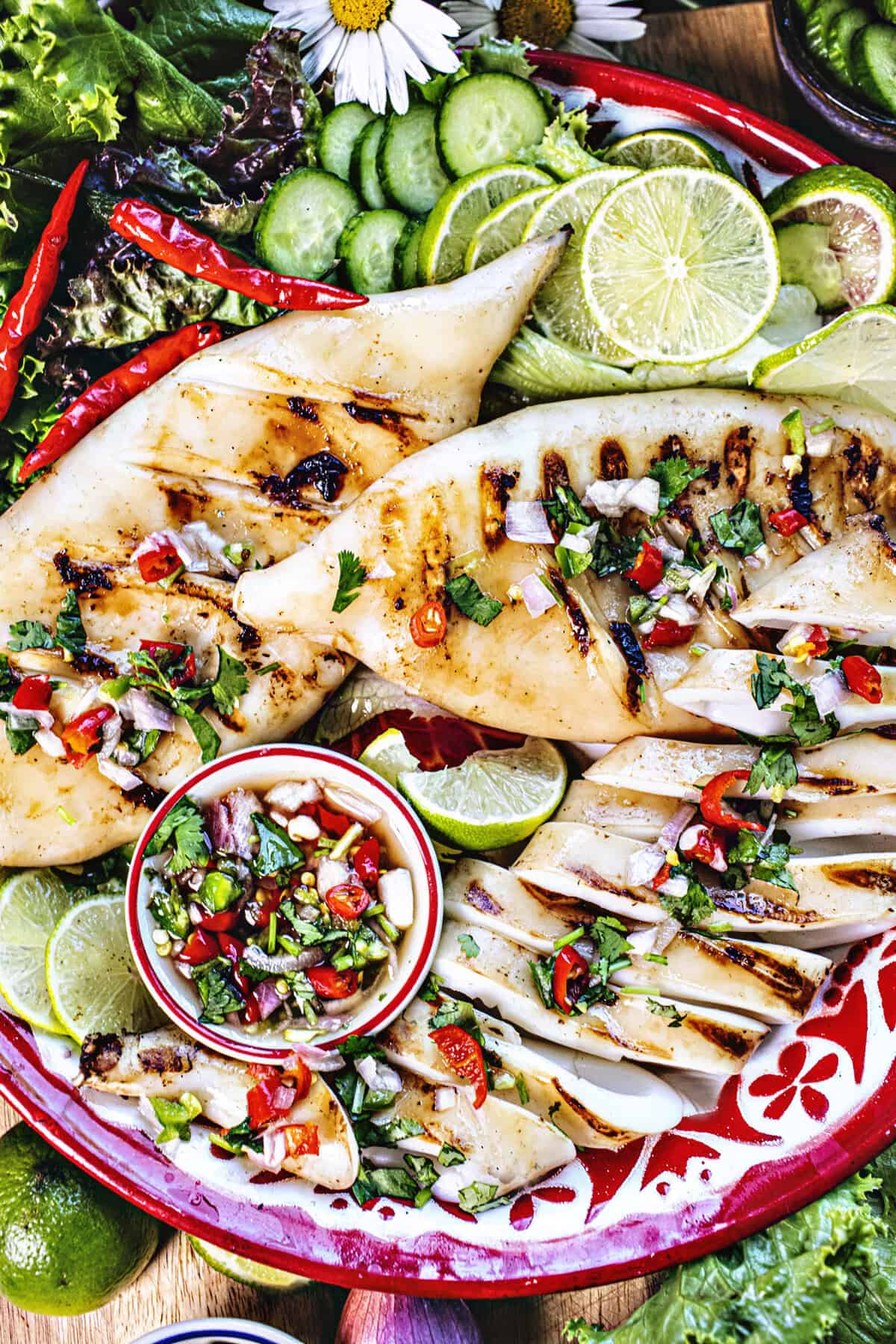Thai Grilled squid a tray with dipping sauce and veggies. 