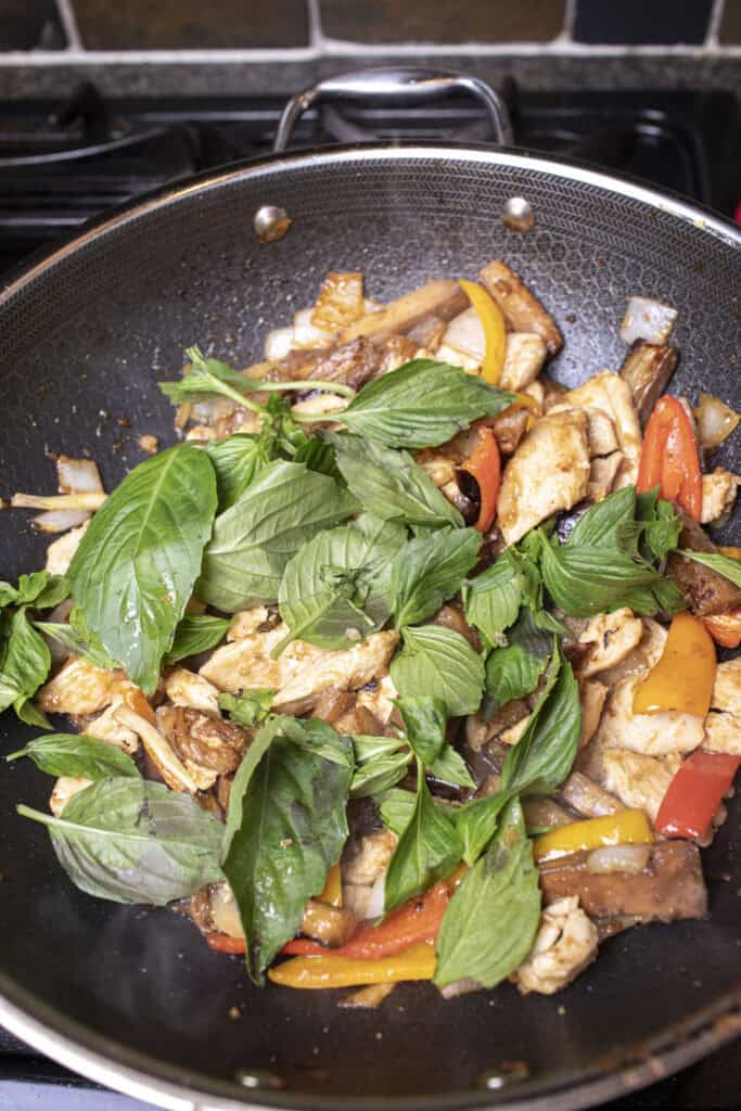 Thai basil in a wok with stir-fried eggplants.