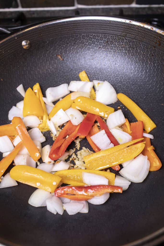 Cooked onion and bell pepper pieces in a wok.