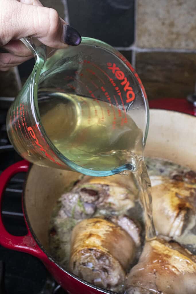 Liquid pouring into a pot with pork hocks.