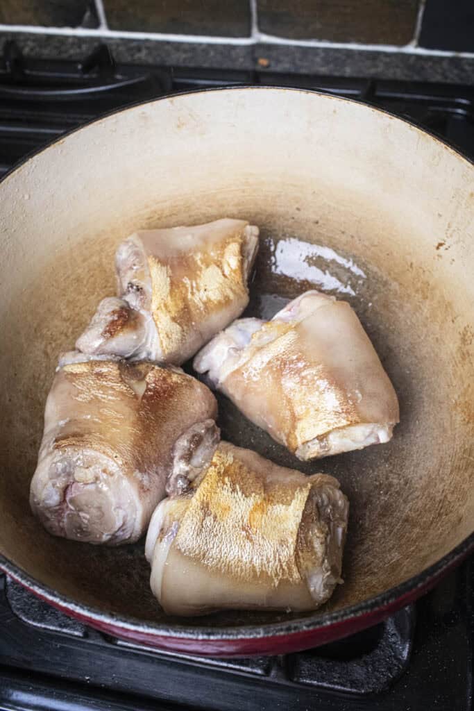 4 Pork hocks browning in a dutch oven. 