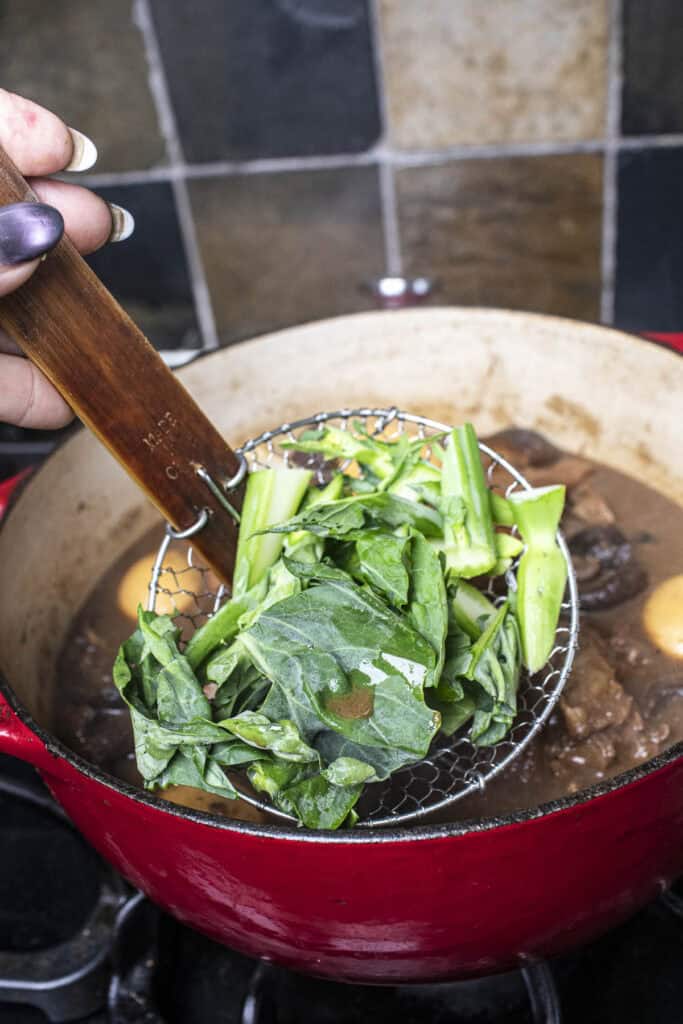 Chinese broccoli in wiremesh over pork stew. 