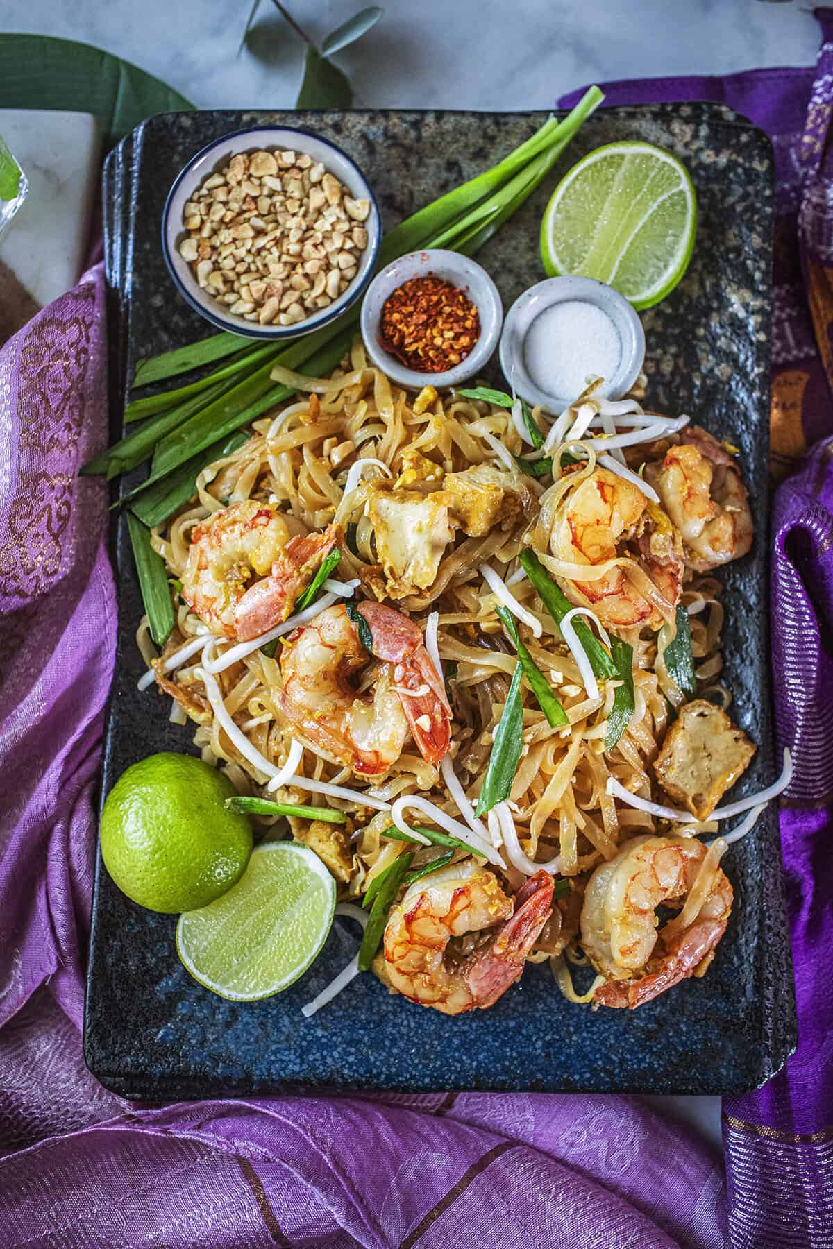 Shrimp Pad Thai on a platter with garnishes. 