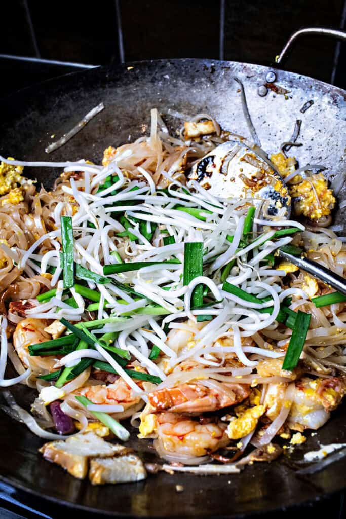 Vegetables over Rice noodles for pad thai in a wok. 