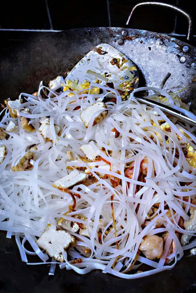 Tossed Rice noodles for pad thai in a wok. 