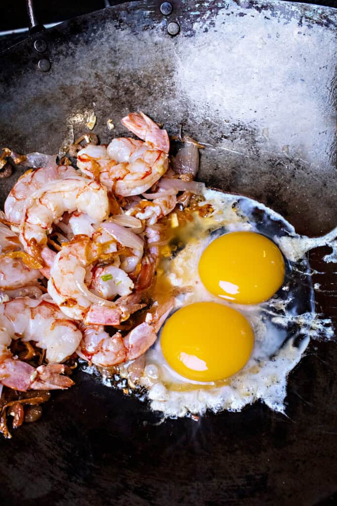 fried shrimp and eggs for pad thai in a wok. 