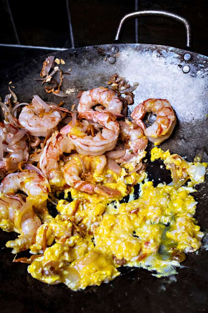 fried scramble eggs and shrimp for pad thai in a wok. 