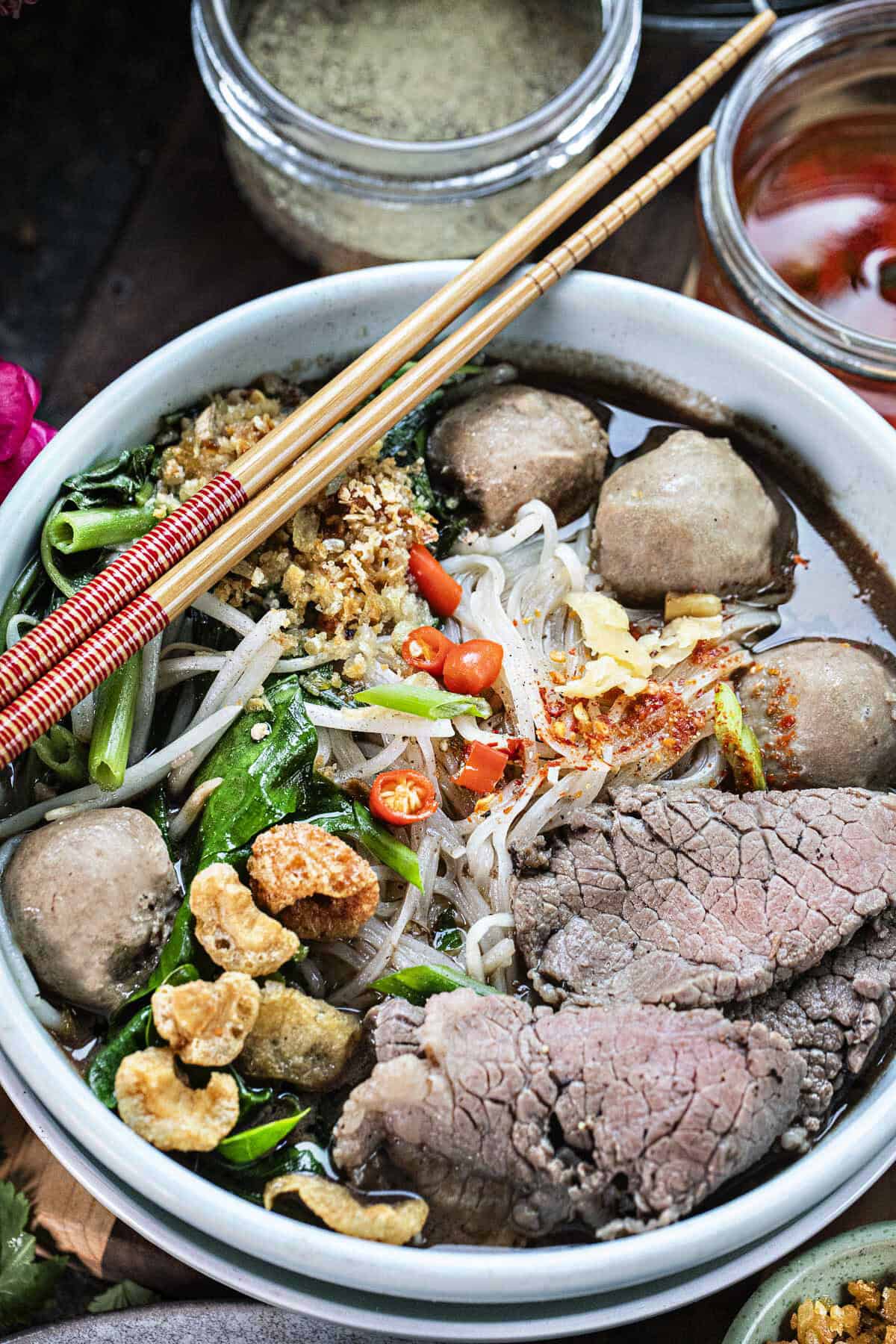 A bowl  of boat noodles soup wih meat, noodles and veggies in a bowl. 
