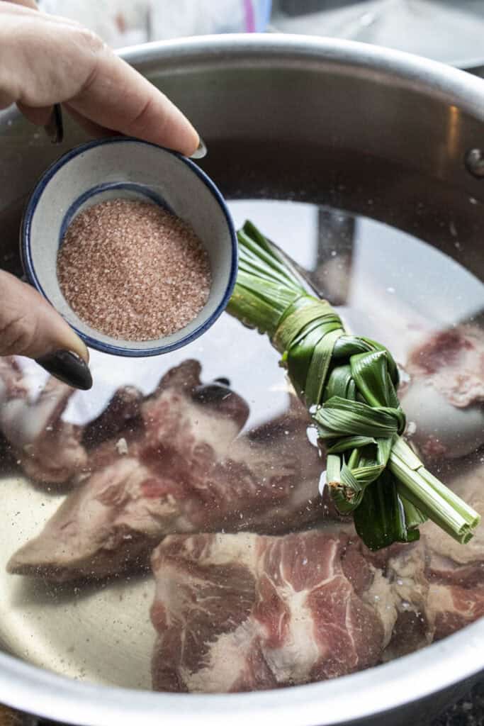 salt, pandan leaves and pork bones for Thai boat noodle soup in a pot.