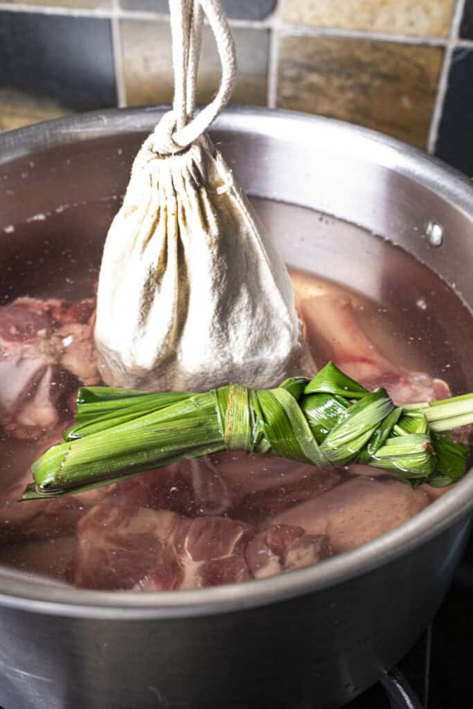 Sachet, pandan leaves and pork bones for Thai boat noodle soup in a pot.