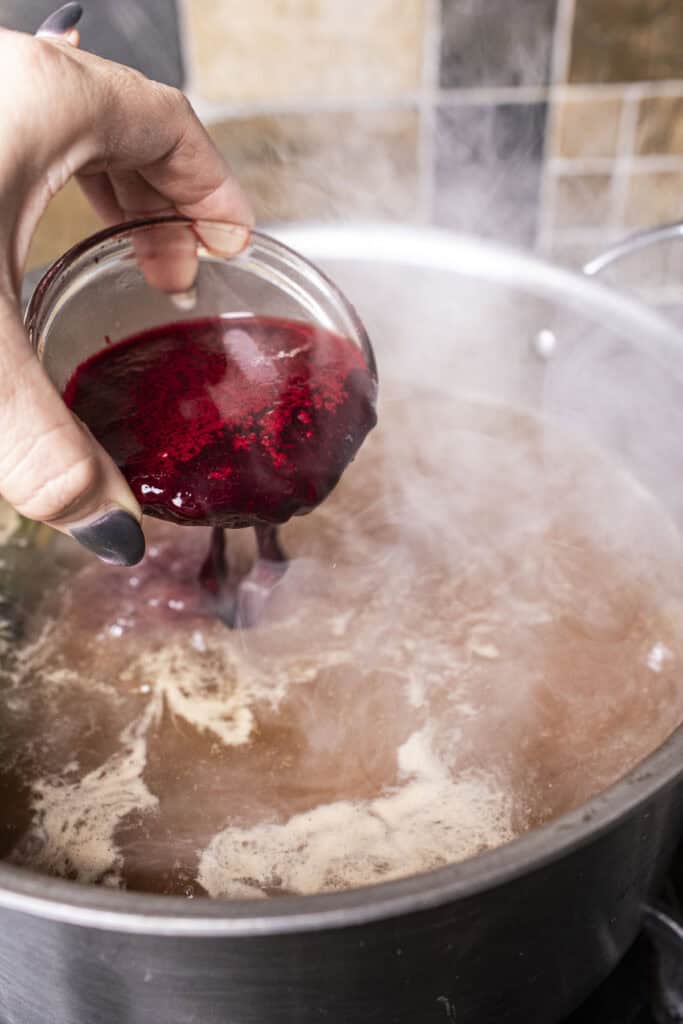 Blood in a bowl pouring into a pot of broth.