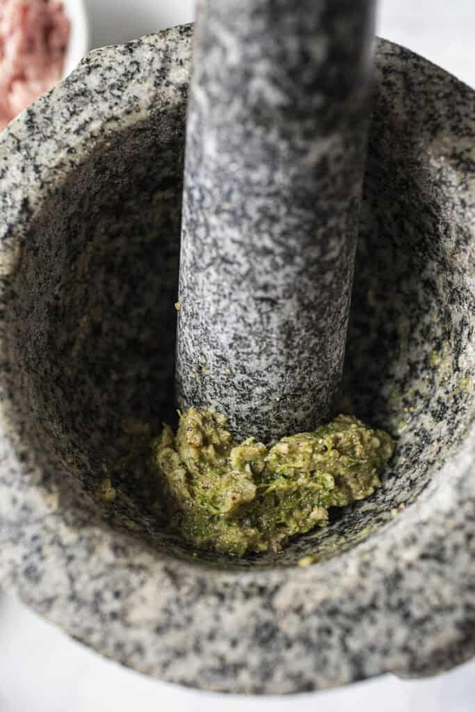 Green Sam Gler Paste in a mortar and pestle. 