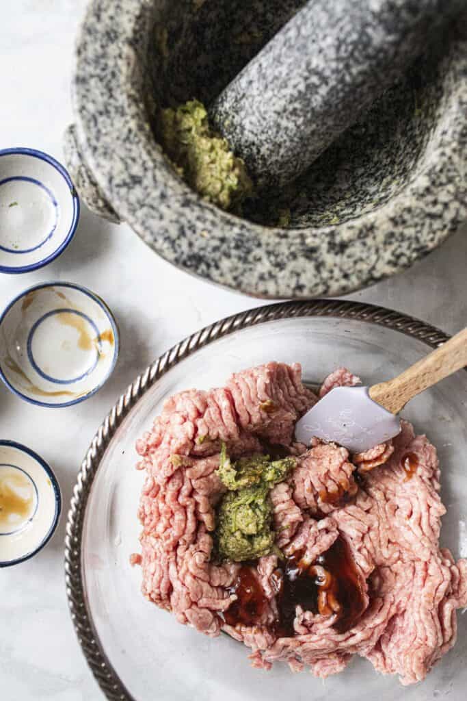 Ground Pork with seasoning sauces in a glass container.