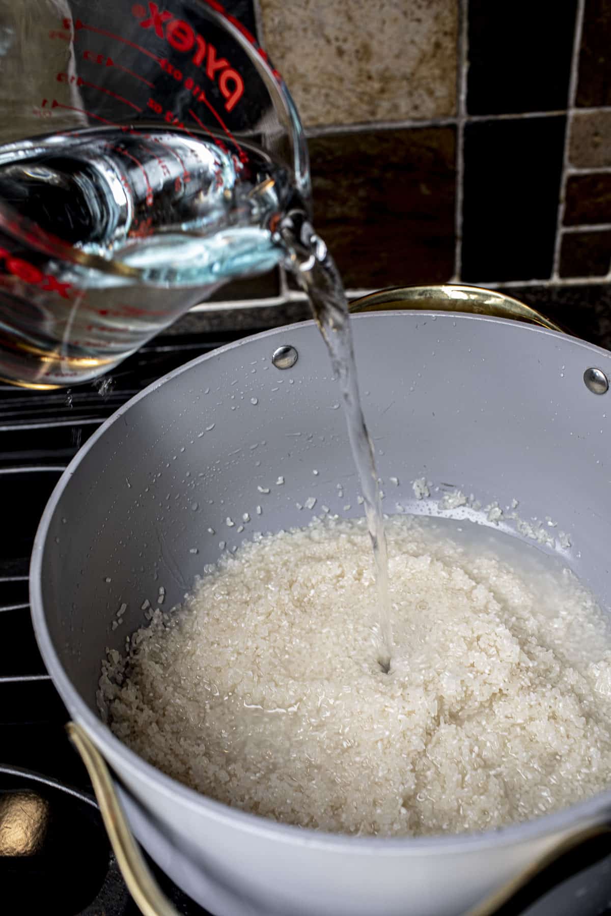water pouring into a pot of Broken rice for Jok.