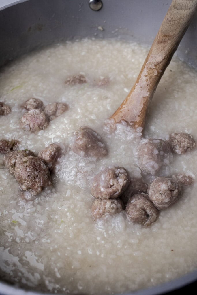 Pork meatballs in rice porriage in a pot.