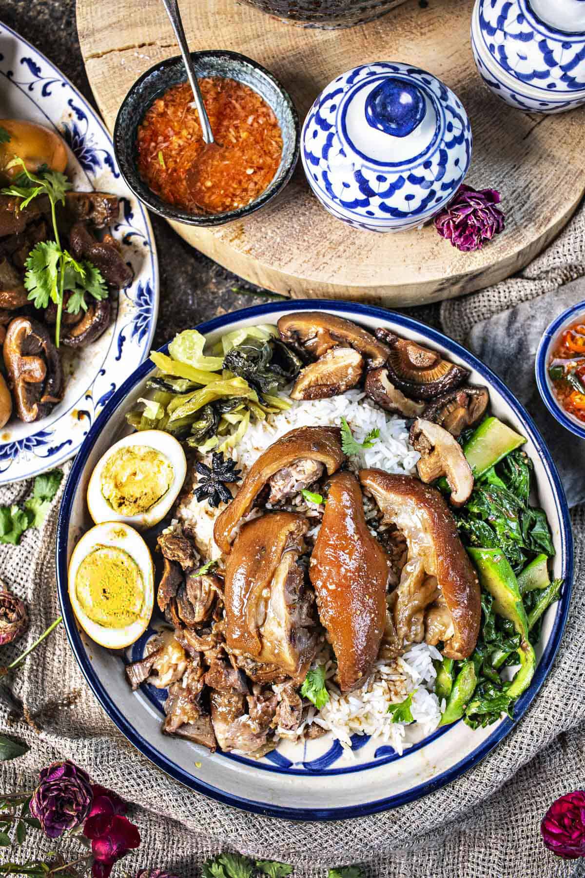 A spoon driping dressing on Khao Ka Moo On a plate.