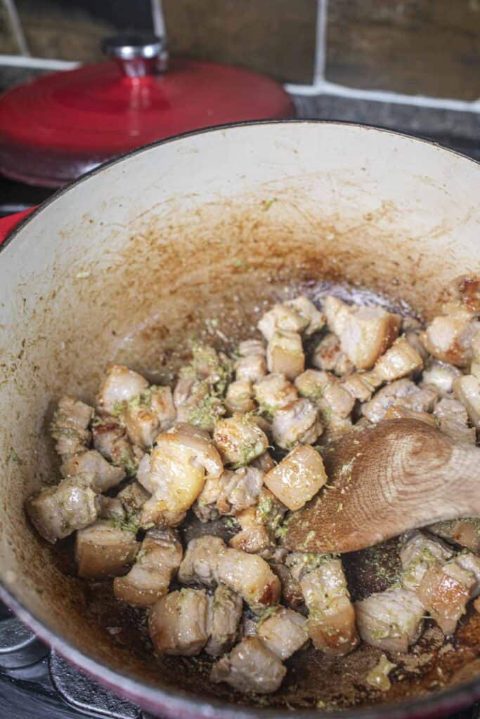 Pork belly cubes with herbs in a dutch oven.