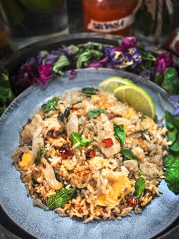 Thai basil fried rice on a plate with lime wedges on the side.