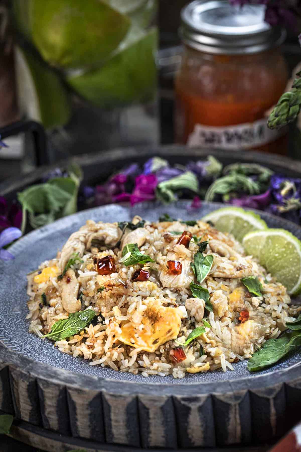 Thai chicken basil fried rice on a plate with lime wedges. 