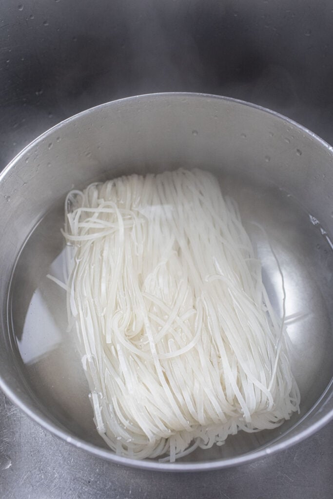 Soak rice noodles in a bowl. 