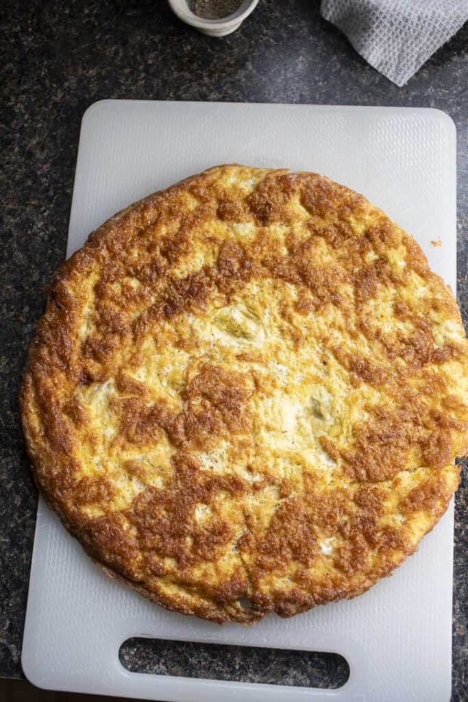 Flat round omelet on a cutting board.