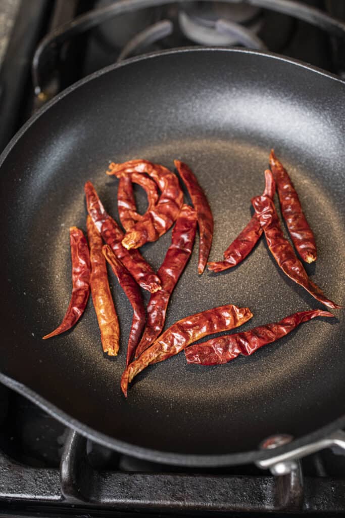 Whole red dried chilis in a small pan over the stove. 