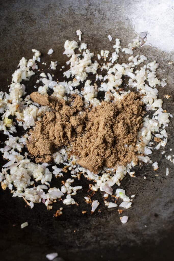 Aromatics and brown sugar in a wok.