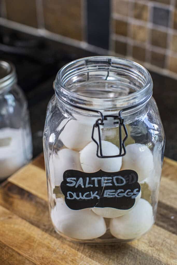 A glass jar with salted duck eggs inside.