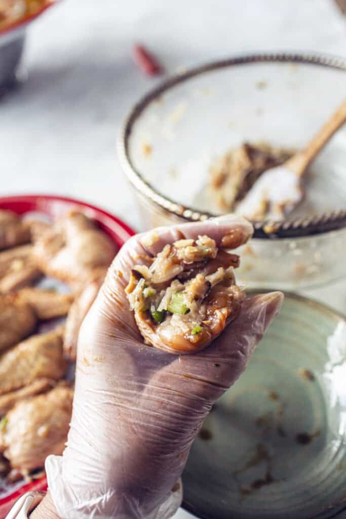 Hand holding Uncooked stuffed wings. 