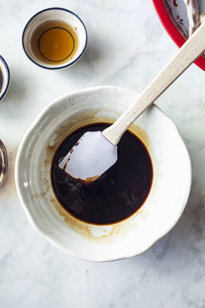 Dark sauce for chicken wings in a white bowl on the table. 