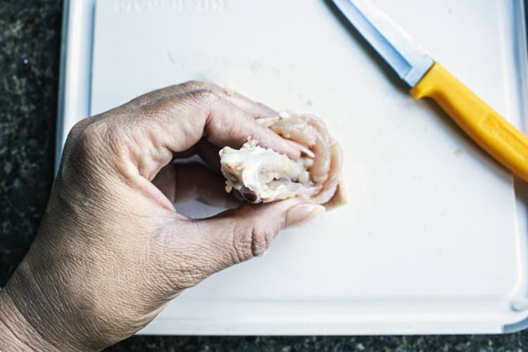 Deboning chicken wing on a cutting b board with a small knife. 