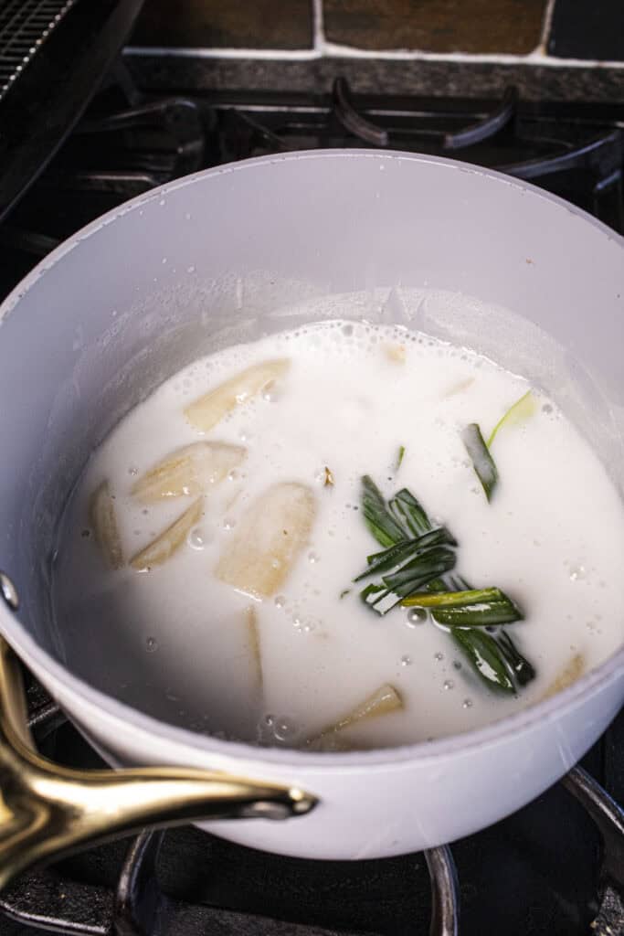 banana, pandan leaves and coconut milk in a pot.