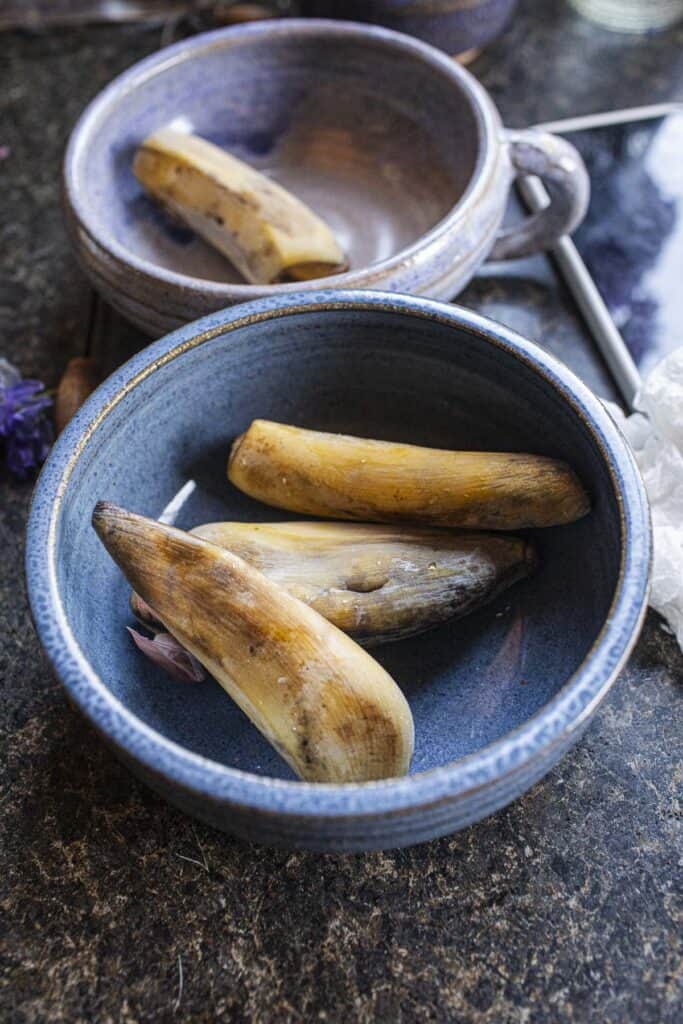 Cooked banana with peels on in bowls. 