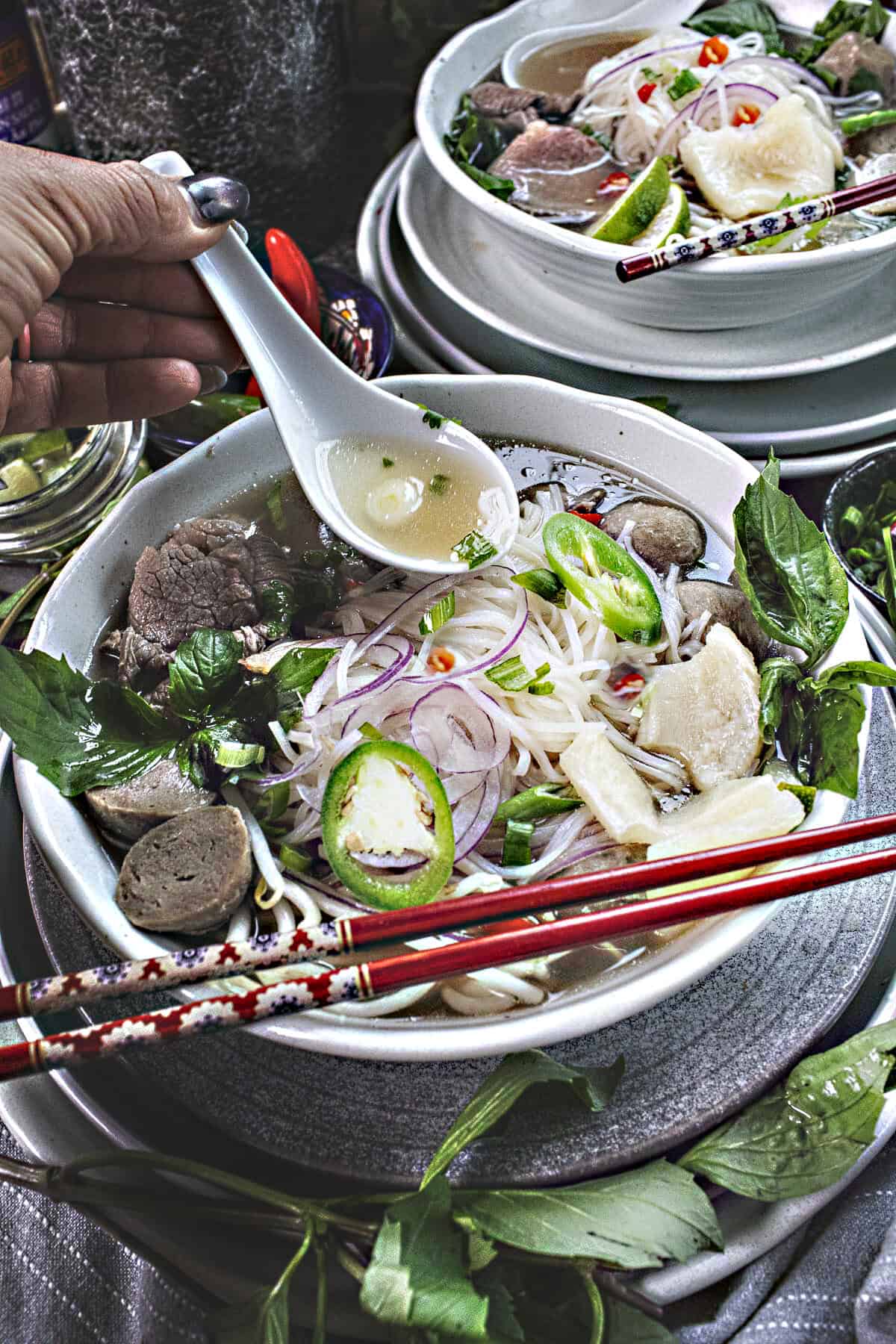 spoon lifting pho broth from a bowl. 
