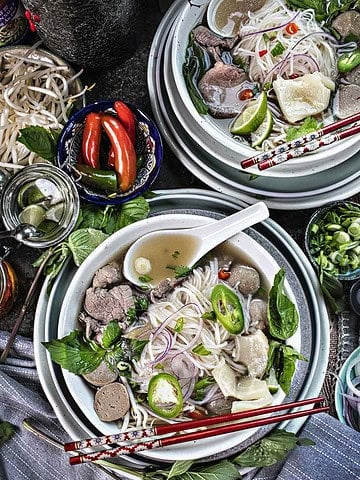 2 bowls of beef pho on the table.