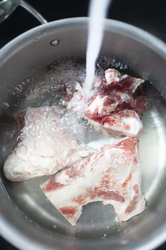 water from faucet running into a pot with Beef bones.