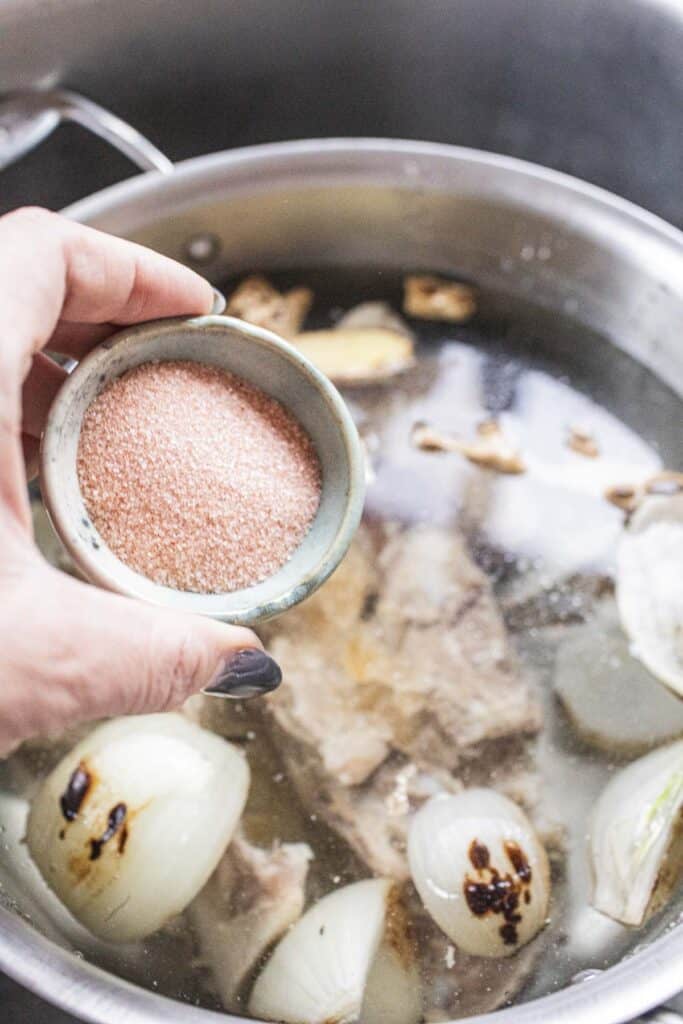 Salt pouring into pho broth.