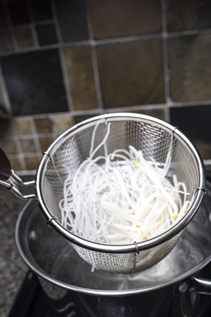Noodles in a wire mesh strainer.