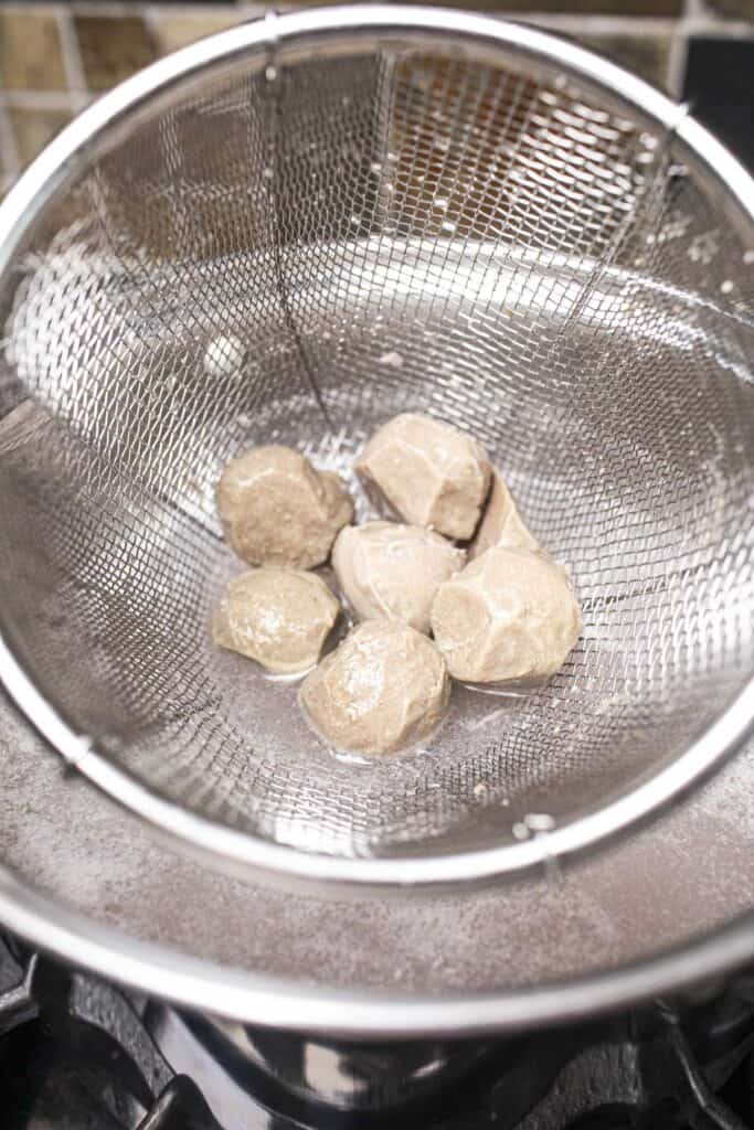 Meatballs in a wire mesh strainer.