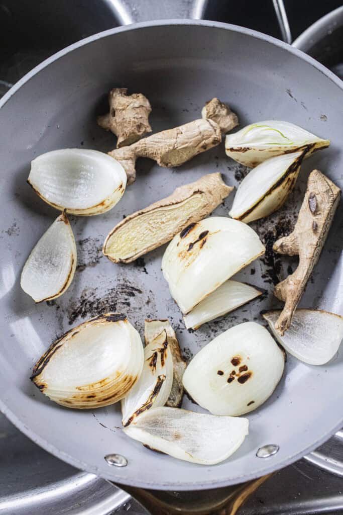 Charred onion and ginger in a pan.