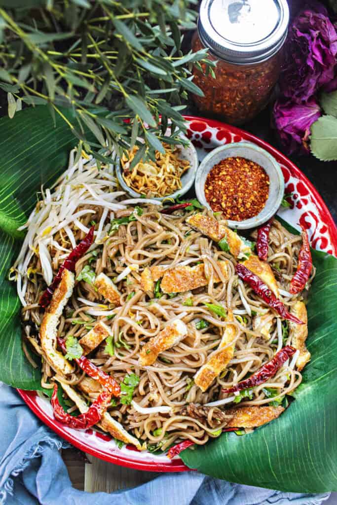 Kua Mee noodles on a red platter with garnishes.