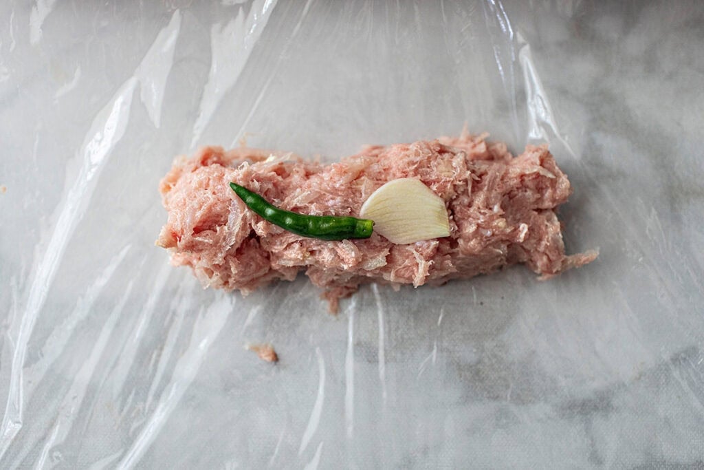 Saran Wrapped sour sausage on a table. 