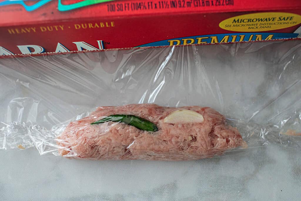 Saran Wrapped lao sausage on a table. 