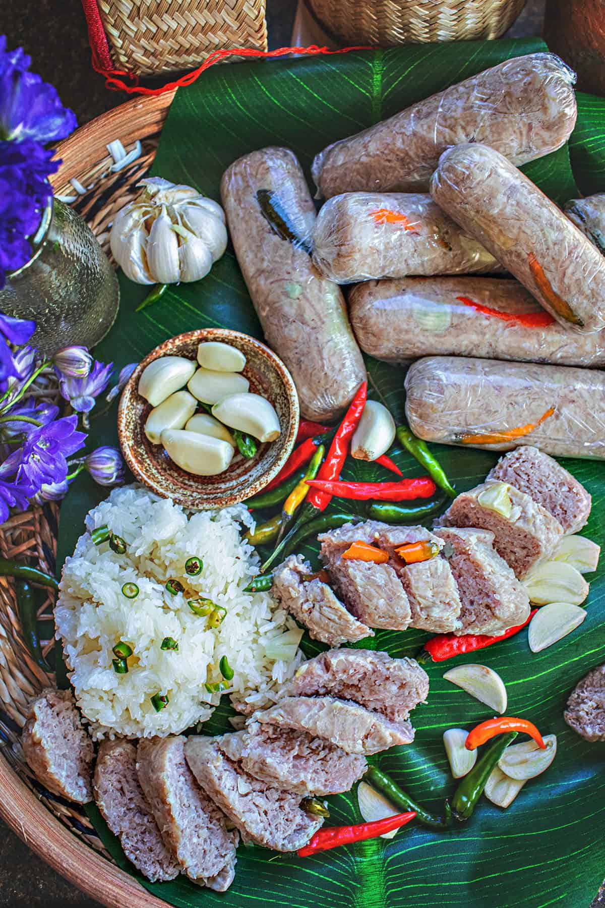 Sliced Lao Nam sour sausage on a platter with rice and Thai chilis. 