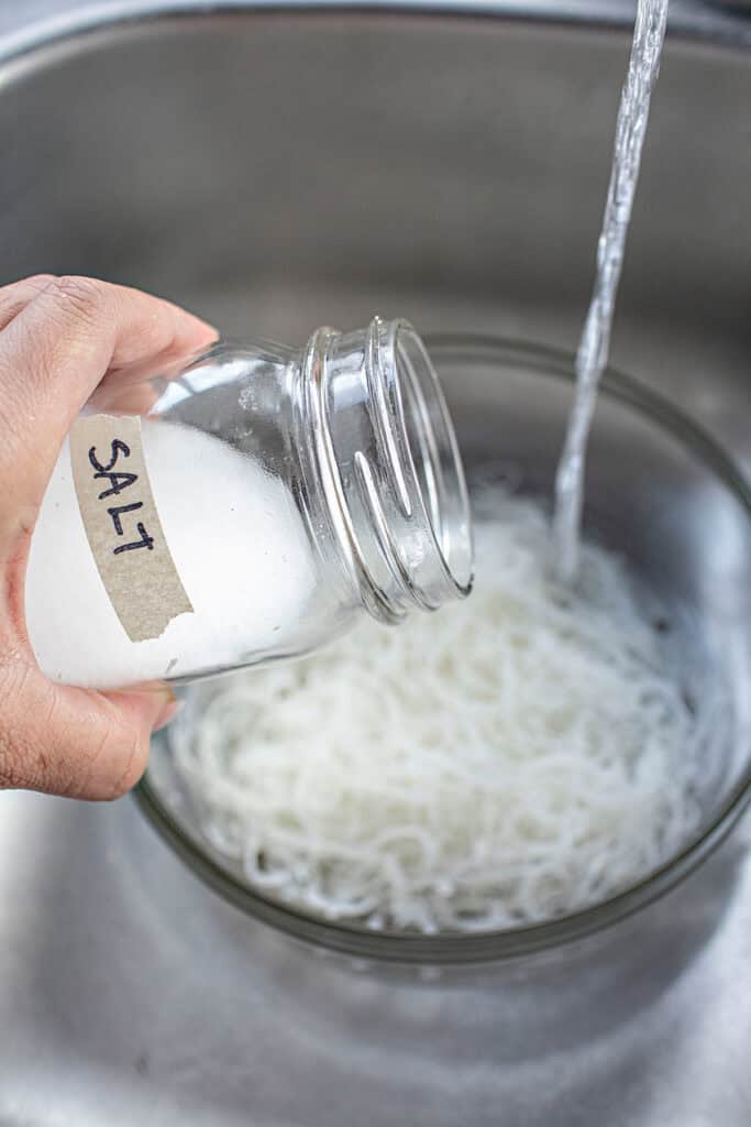 Salt poured into pork skin in a colander in a sink.