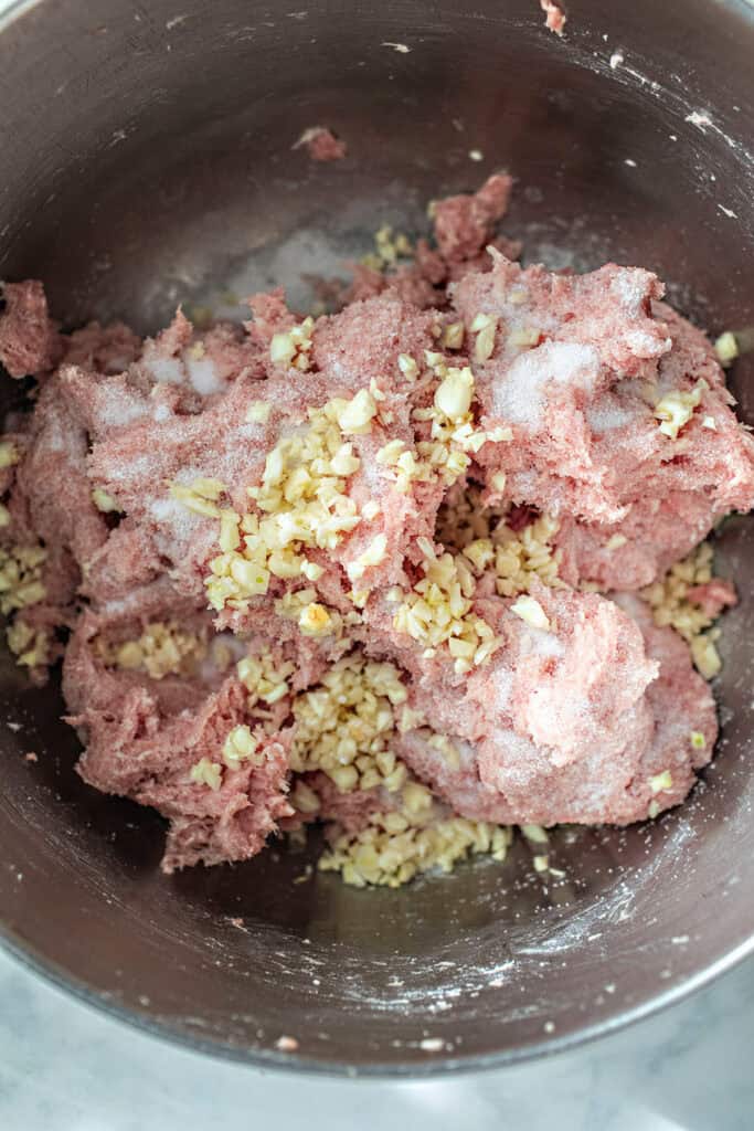 Ground pork with miced garlic in a bowl.