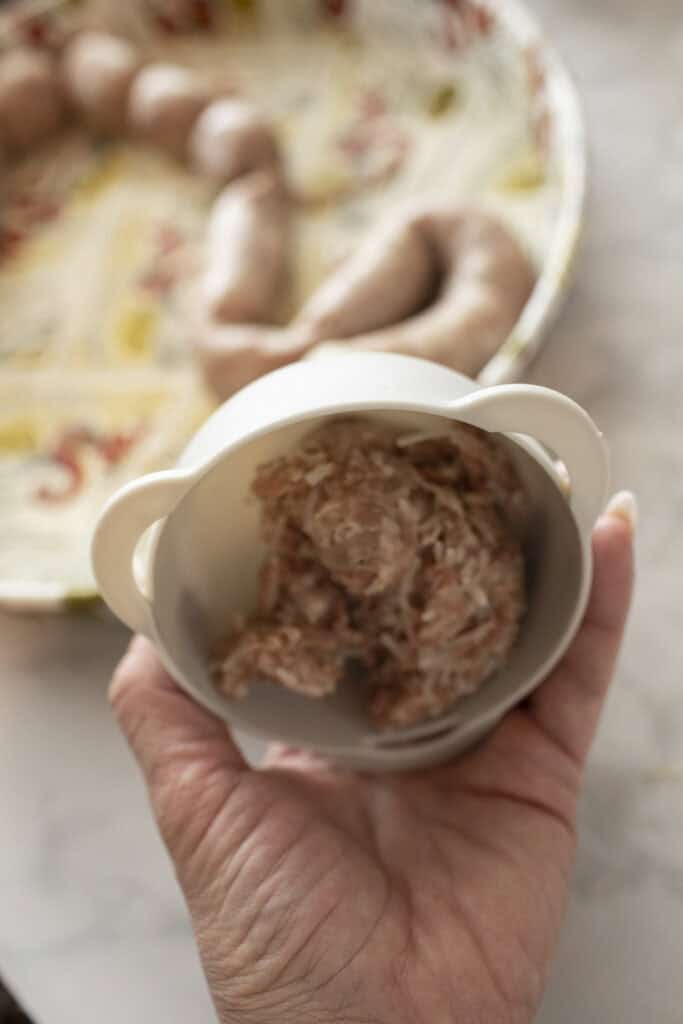 Hand holding funnel for stuffing sausage. 