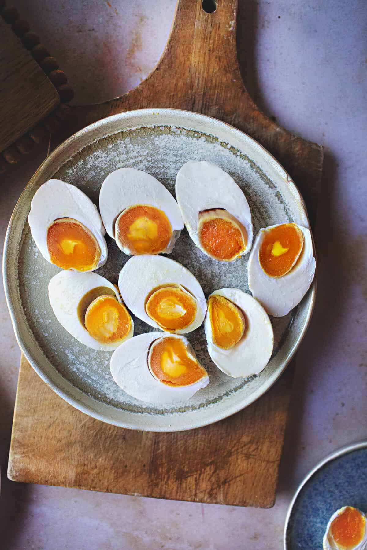 Sliced salted duck eggs on a plate on a cutting board. 